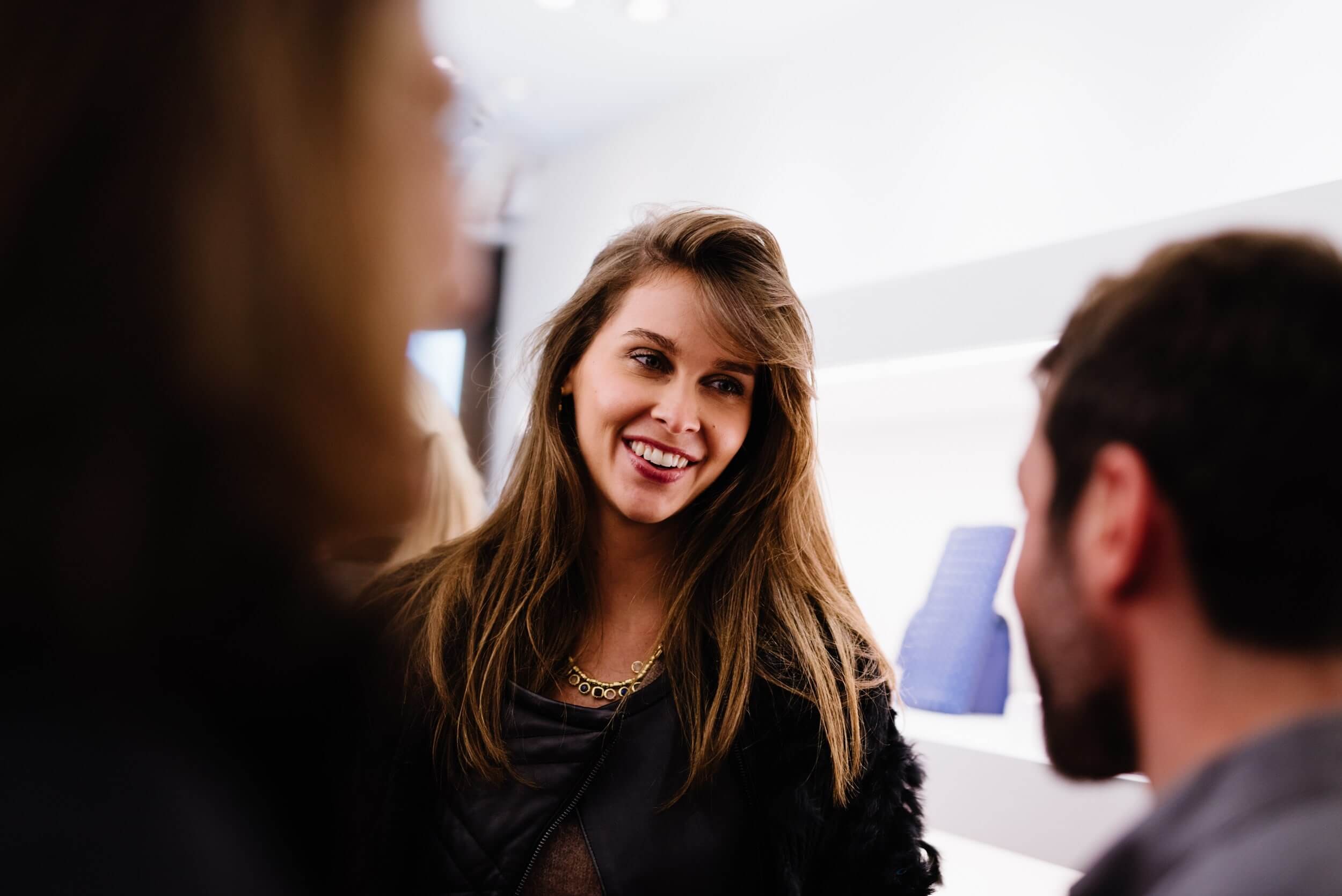 Invitée souriante photographiée pendant un cocktail professionnel, portrait pris sur le vif dans la foule, photographe événementiel Paris
