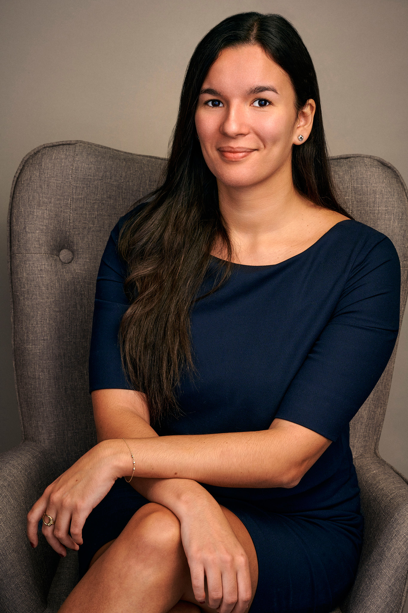Portrait corporate d'une femme assise en robe bleu marine, sourire discret, par Pierre-Yves Queignec, photographe corporate à Paris